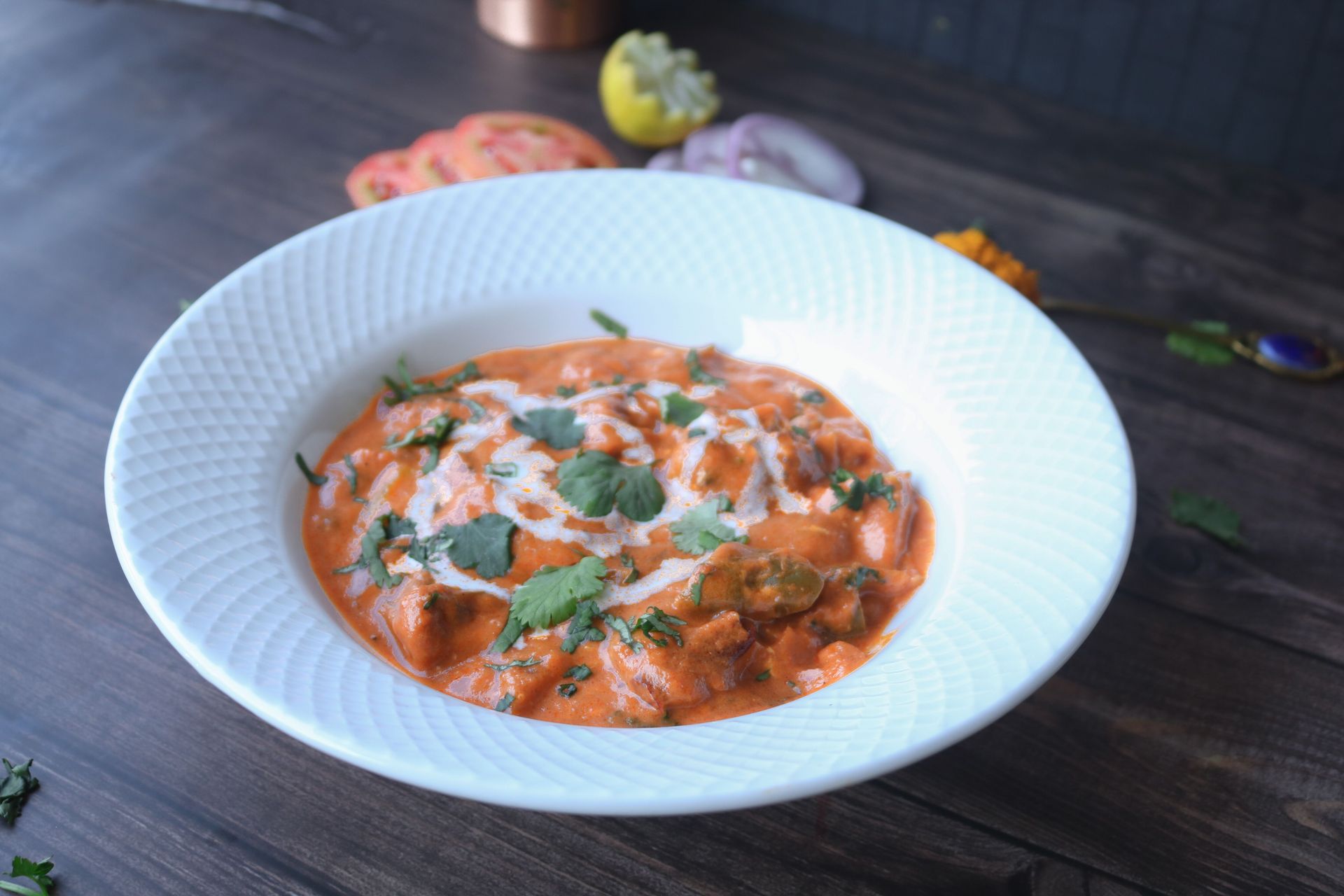 Mouthwatering paneer butter masala garnished with fresh herbs on a white plate.